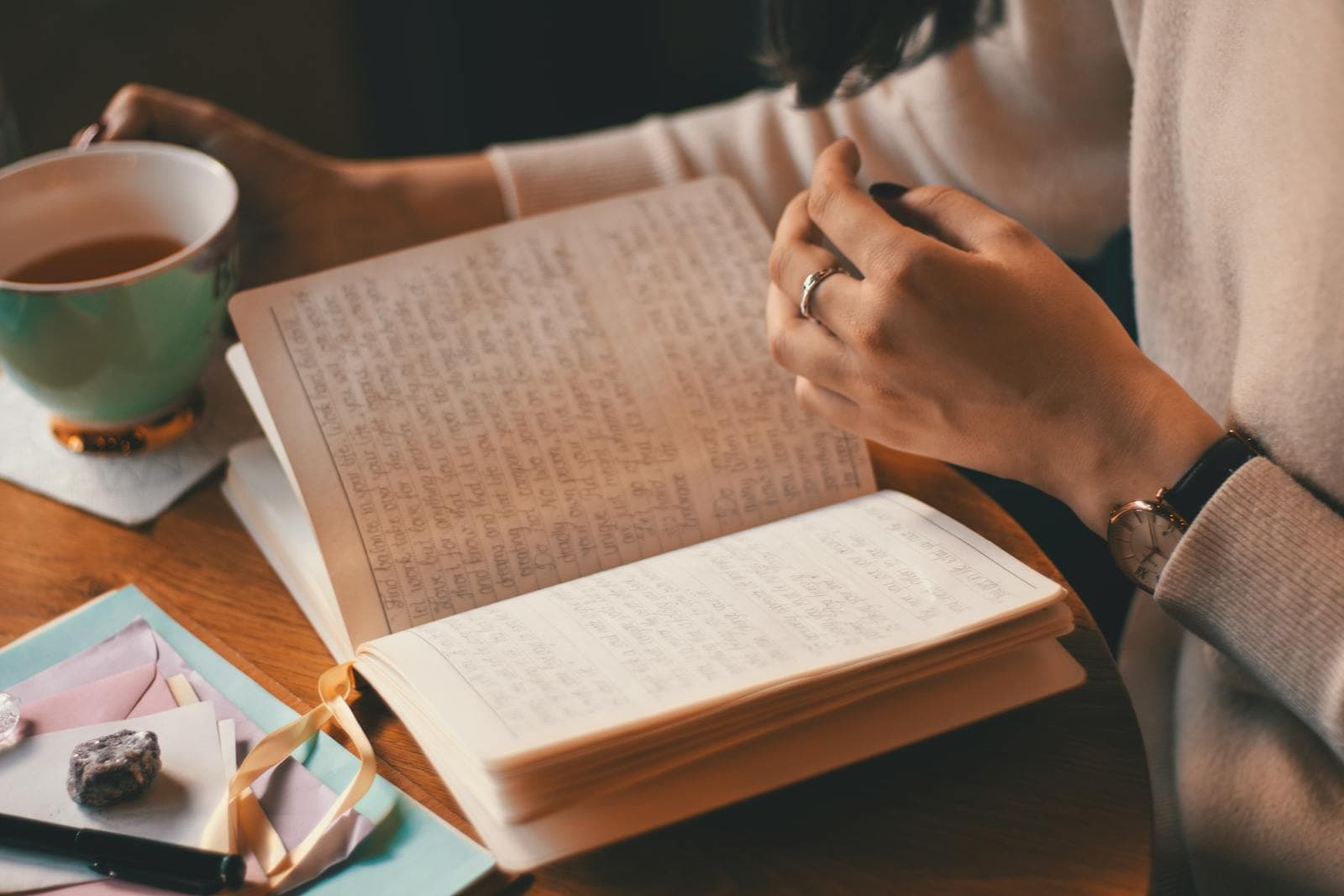 Hände mit Journal, Tee und Notizen